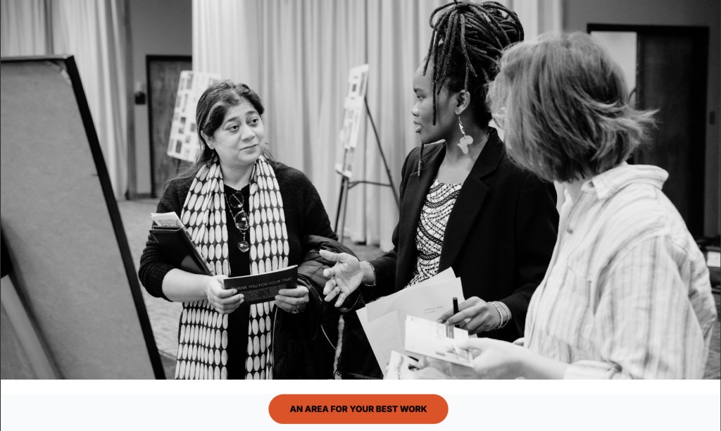 Three women collaborating at a professional event with presentation materials